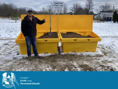 Man standing beside filled sand bins