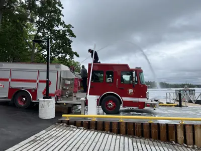fire truck by dock with fire hose spray