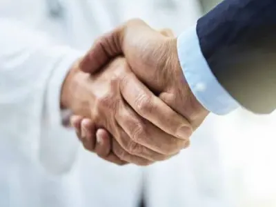 Hand shake between a Dr and a business person