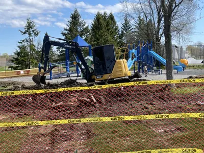 Backhoe digging dirt in a new playground equipment installation