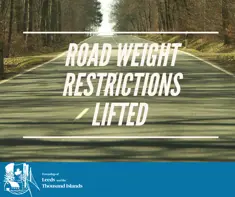 Paved road with trees on both sides, text reads Road Weight Restrictions Lifted