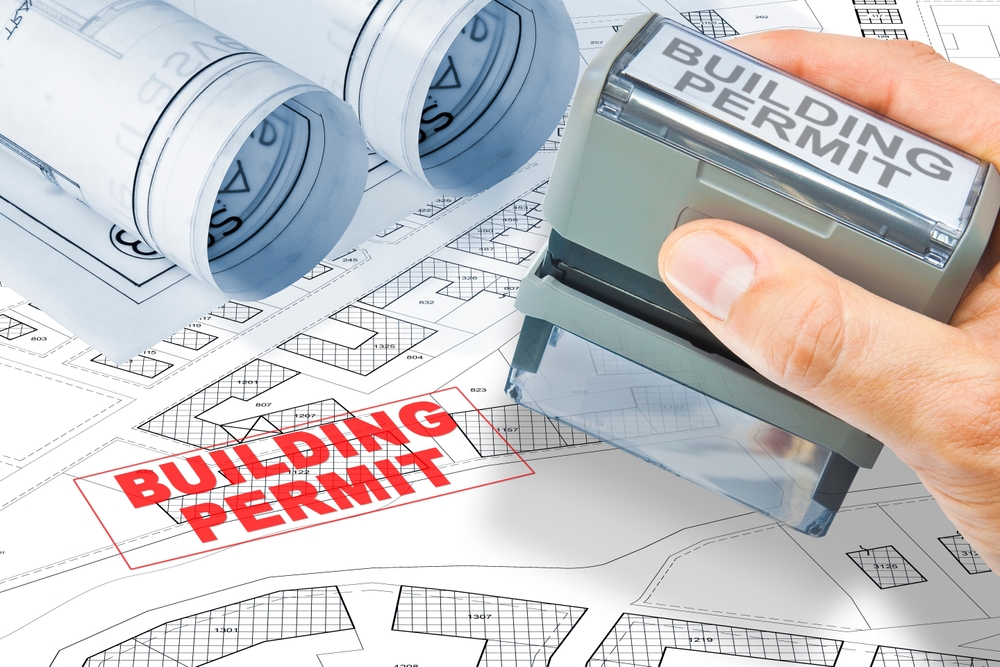 Site plan with a stamp saying building permit.  There is a hand holding a building permit stamper