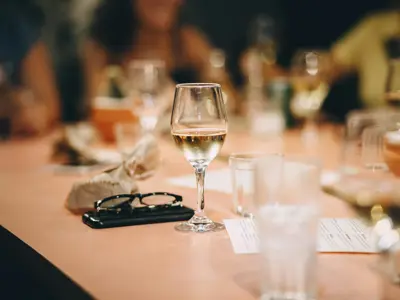 a glass of wine, a pair of sunglasses and water glasses on a table